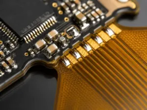Rigid-flex PCBA assembly detail showing SMT components on the rigid section transitioning to a matte polyimide flexible circuit area for complex electronic manufacturing.